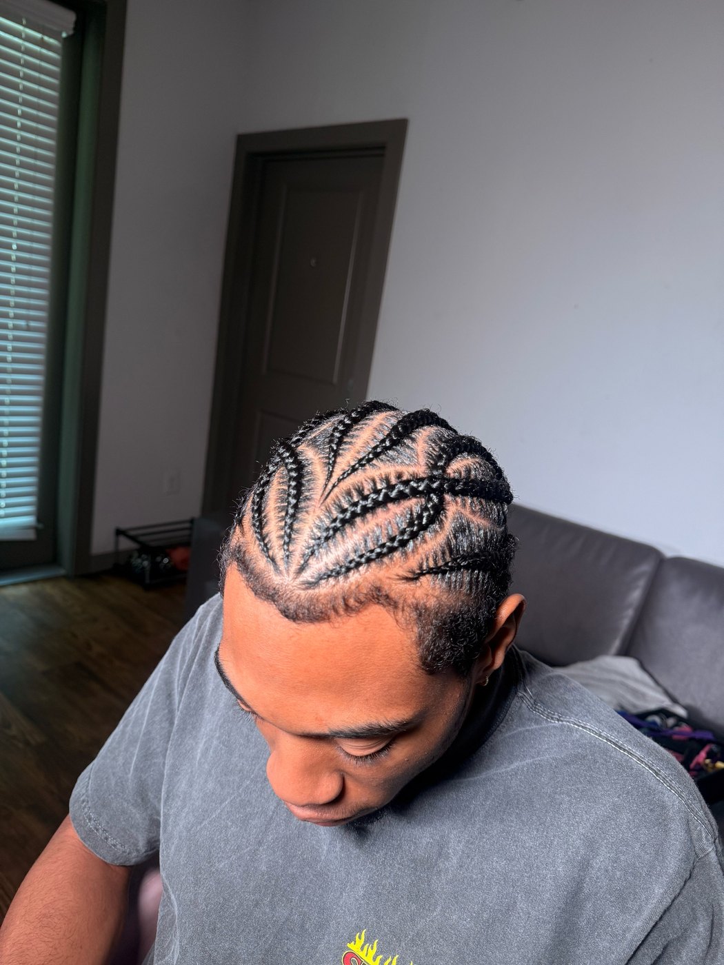 A finished set of men's stitch braids, side view against a brick wall