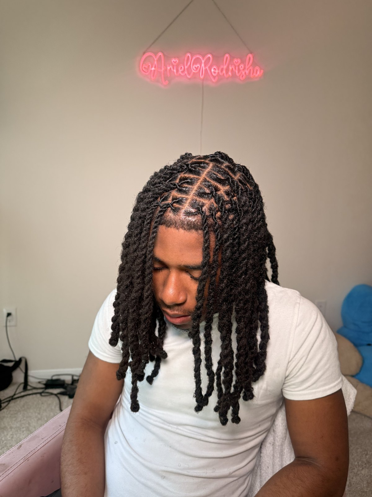 A male client with shoulder-length twist braids, seen from above