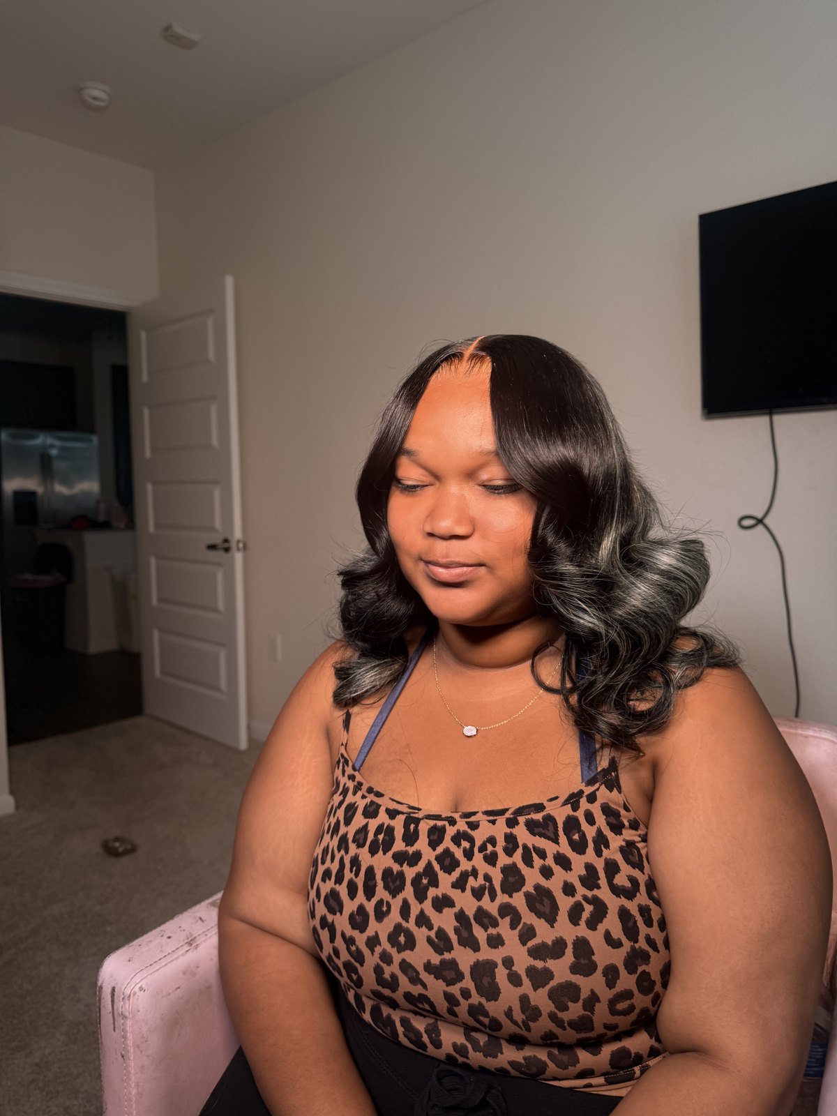 A wavy silver-grey highlighted install, the client seated in the styling chair